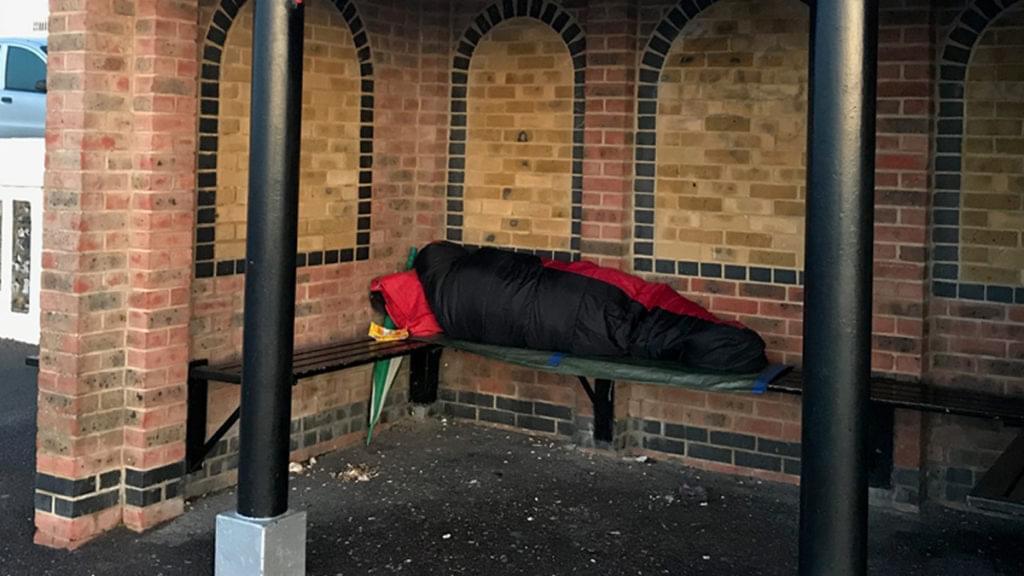 A homeless person sleeping in a beach shelter