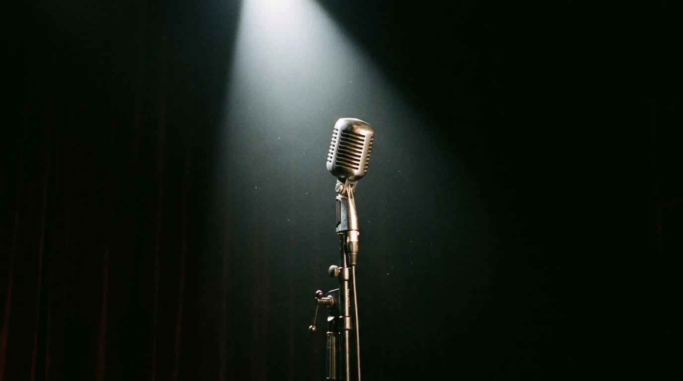 A microphone under a spotlight on a dark stage.