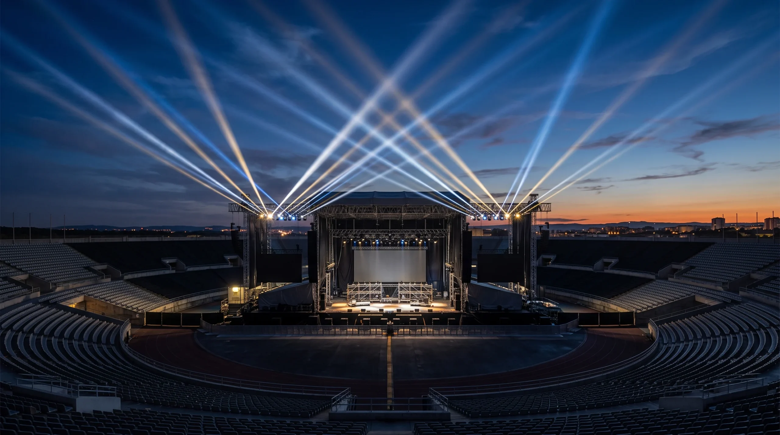 A large outdoor stadium stage with bright spotlights at dusk.